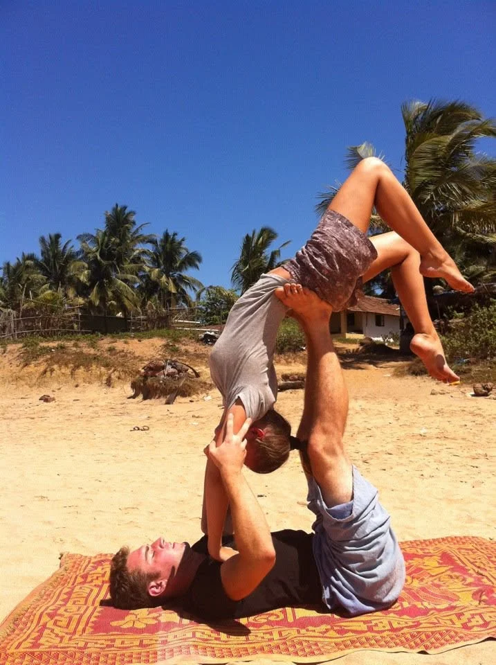 Acro yoga under the palms: balancing on a partner’s feet, hands joined