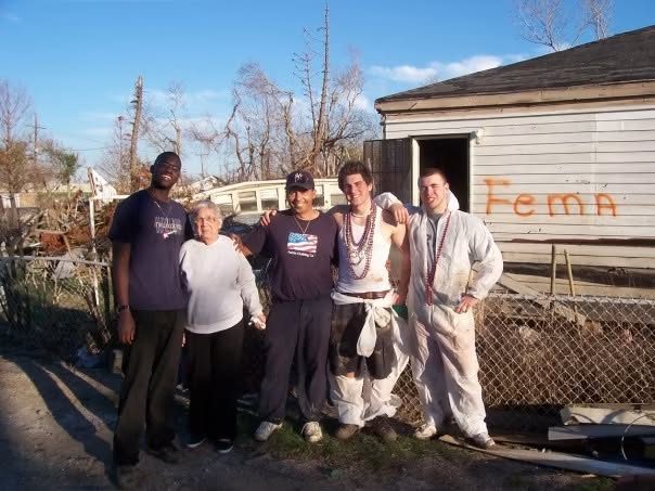 Volunteers with a resident beside a storm-damaged house marked FEMA in New Orleans
