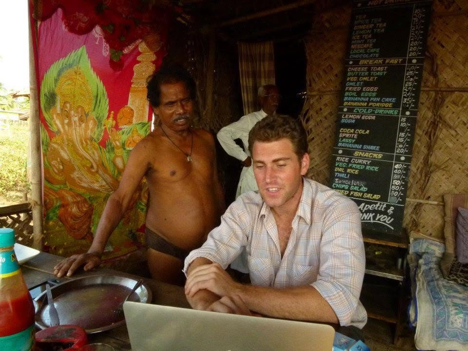 Working on a laptop in a beach café in India, under a hand-painted menu board