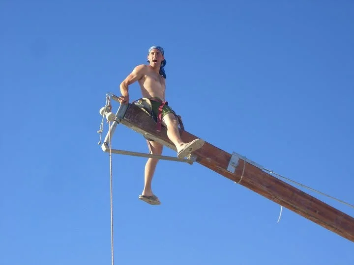 Sitting out at the end of a wooden boom, high against a clear blue sky